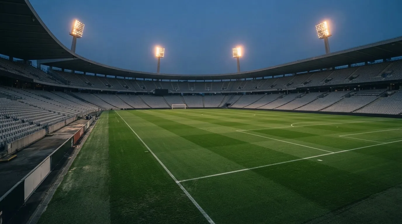 Een leeg voetbalstadion met lichtmasten bij schemering