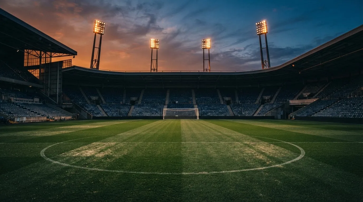 Een leeg voetbalstadion met lichtmasten bij schemering