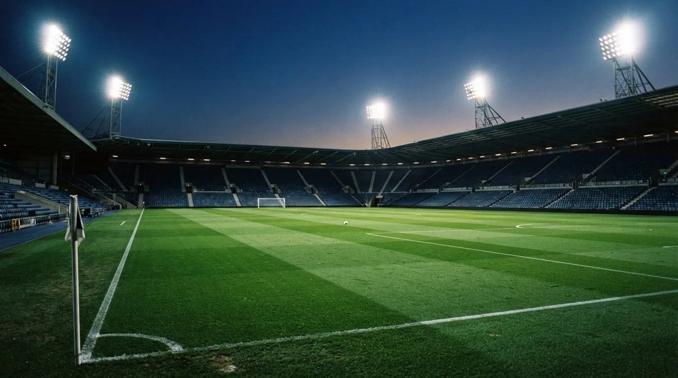 Een leeg voetbalstadion met lichtmasten bij schemering