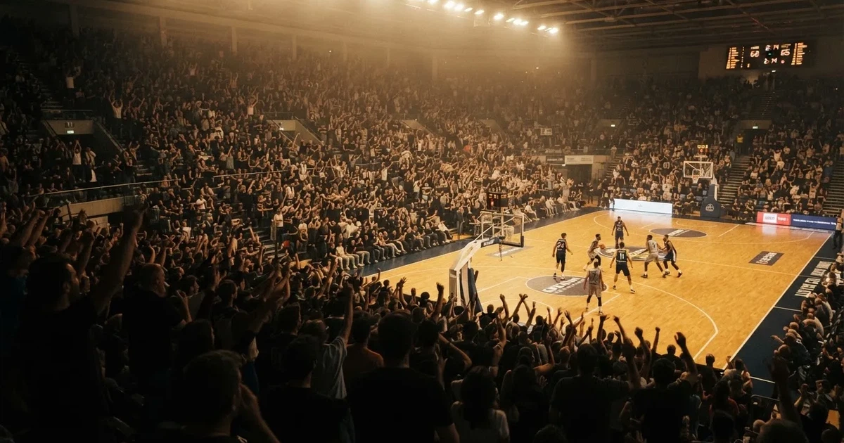 Een volle sporthal onder schijnwerpers, van grote afstand gefotografeerd