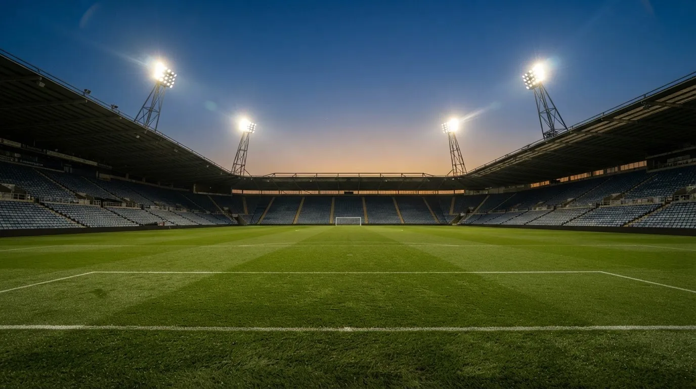 Een leeg voetbalstadion met lichtmasten bij schemering