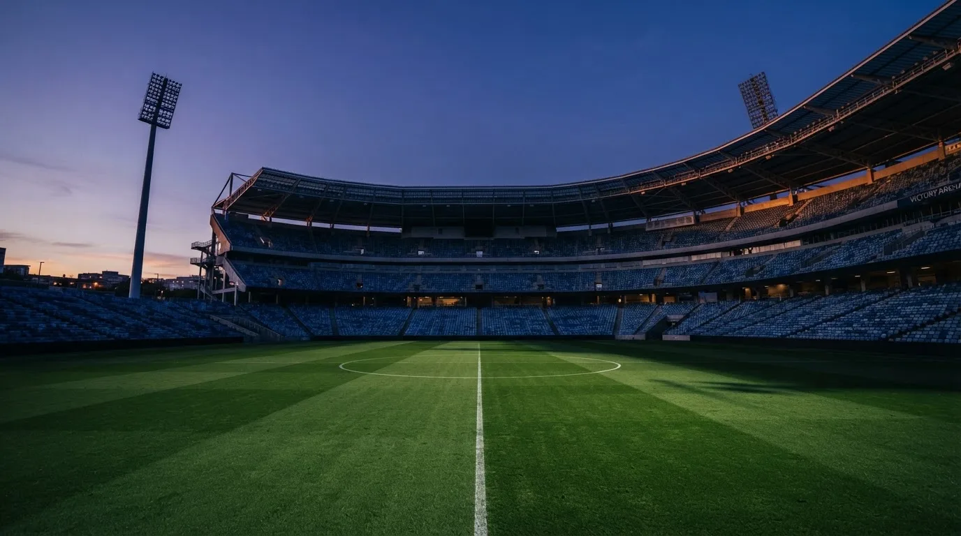Een leeg voetbalstadion met lichtmasten bij schemering