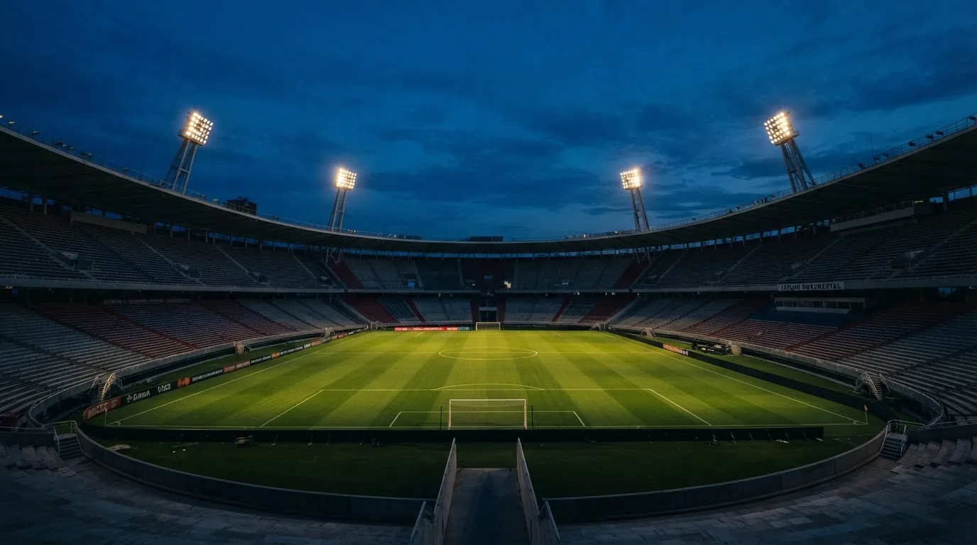Een leeg voetbalstadion met lichtmasten bij schemering