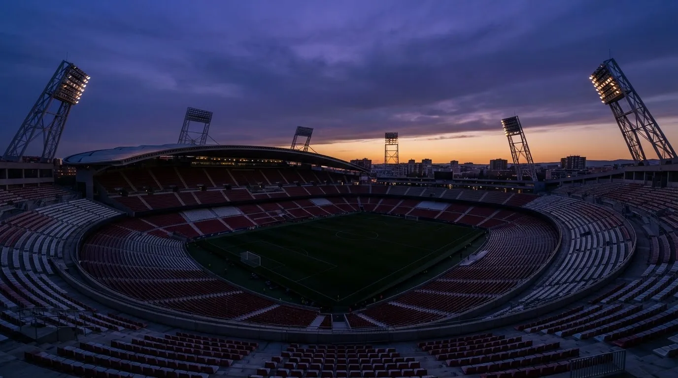Een leeg voetbalstadion met lichtmasten bij schemering